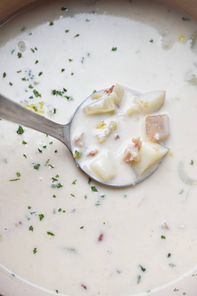 A ladle is scooping out the New England Clam Chowder.