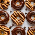 Nine baked peanut butter donuts are shown with five of them having a peanut butter swirl on them.