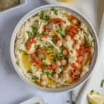 An overhead shot of a bowl of hummus topped with sun dried tomatoes