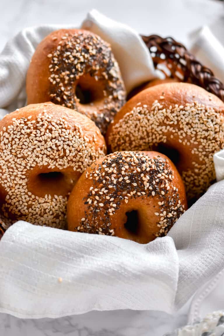 A basket of sesame and everything sourdough bagels is shown.