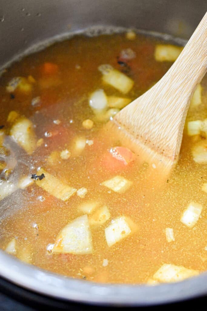 The broth and the chopped tomatoes are added to the rest of the ingredients.