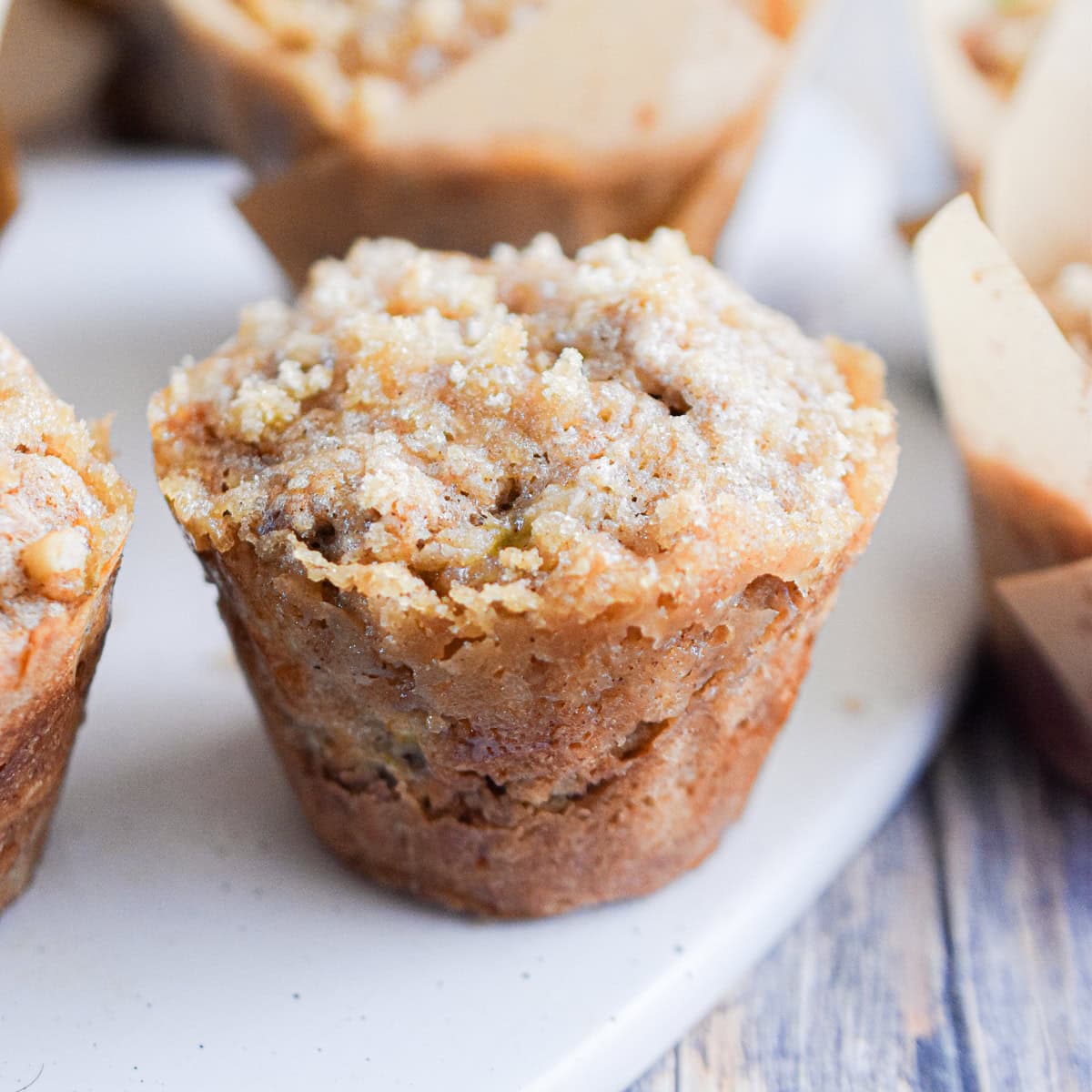 The sourdough banana muffin is on a white cutting board surrounded by other muffins.