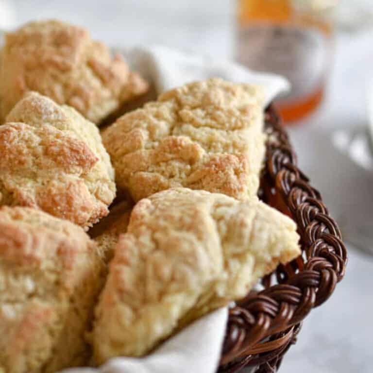 The sourdough discard scones are in a wicker basket with jam in the background.