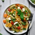 Single plate of garden vegetable and herb pasta salad with a basil garnish