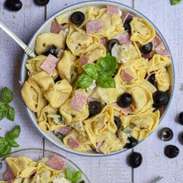 a small plate of salad is served with the large bowl of 10 minute tuscan tortellini salad