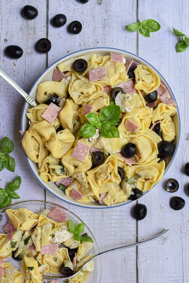 a small plate of salad is served with the large bowl of 10 minute tuscan tortellini salad