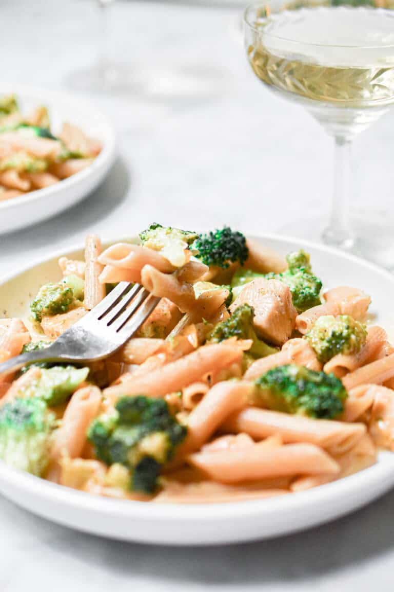 Some of the one pot chicken broccoli pasta is on a fork laying on the plate.