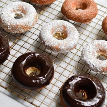 A close up of the sourdough doughnuts, some covered in cinnamon sugar, some covered in chocolate icing, some covered in powdered sugar