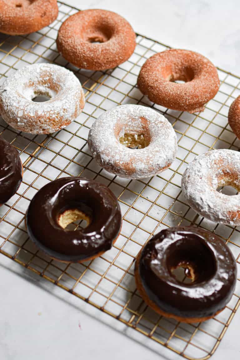 A close up of the sourdough doughnuts, some covered in cinnamon sugar, some covered in chocolate icing, some covered in powdered sugar