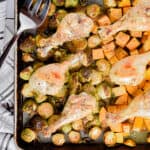 The chicken drumstick sheet pan dinner is laid out with a serving fork on the sheet pan