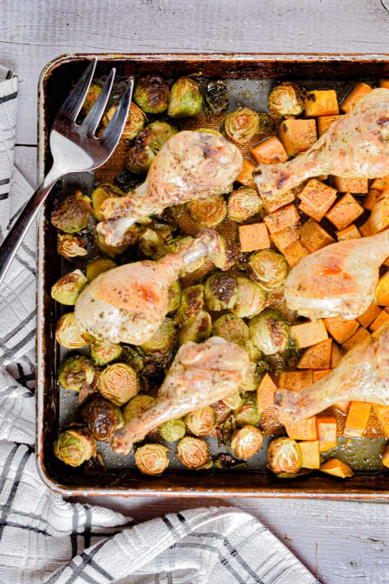 The chicken drumstick sheet pan dinner is laid out with a serving fork on the sheet pan