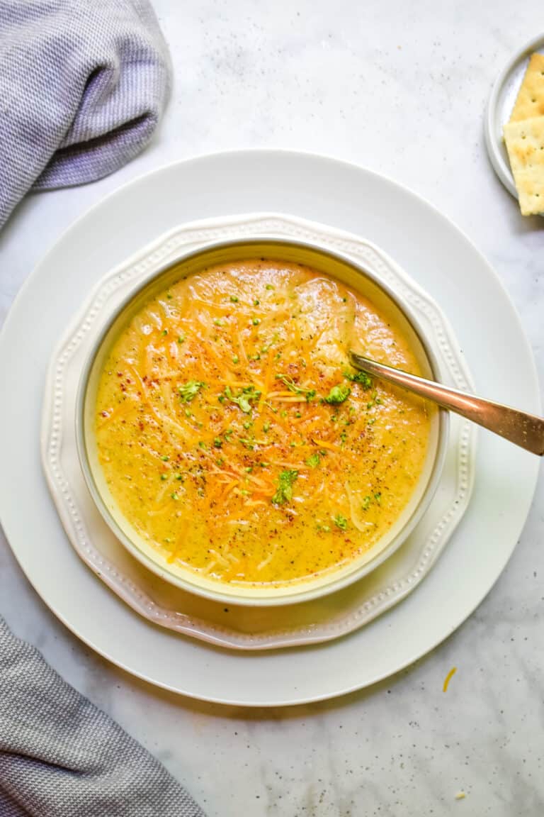 An overhead view of the roasted broccoli and cauliflower soup with a spoon in the bowl