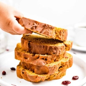 A child's hand is reaching for a stack of the pumpkin soda bread