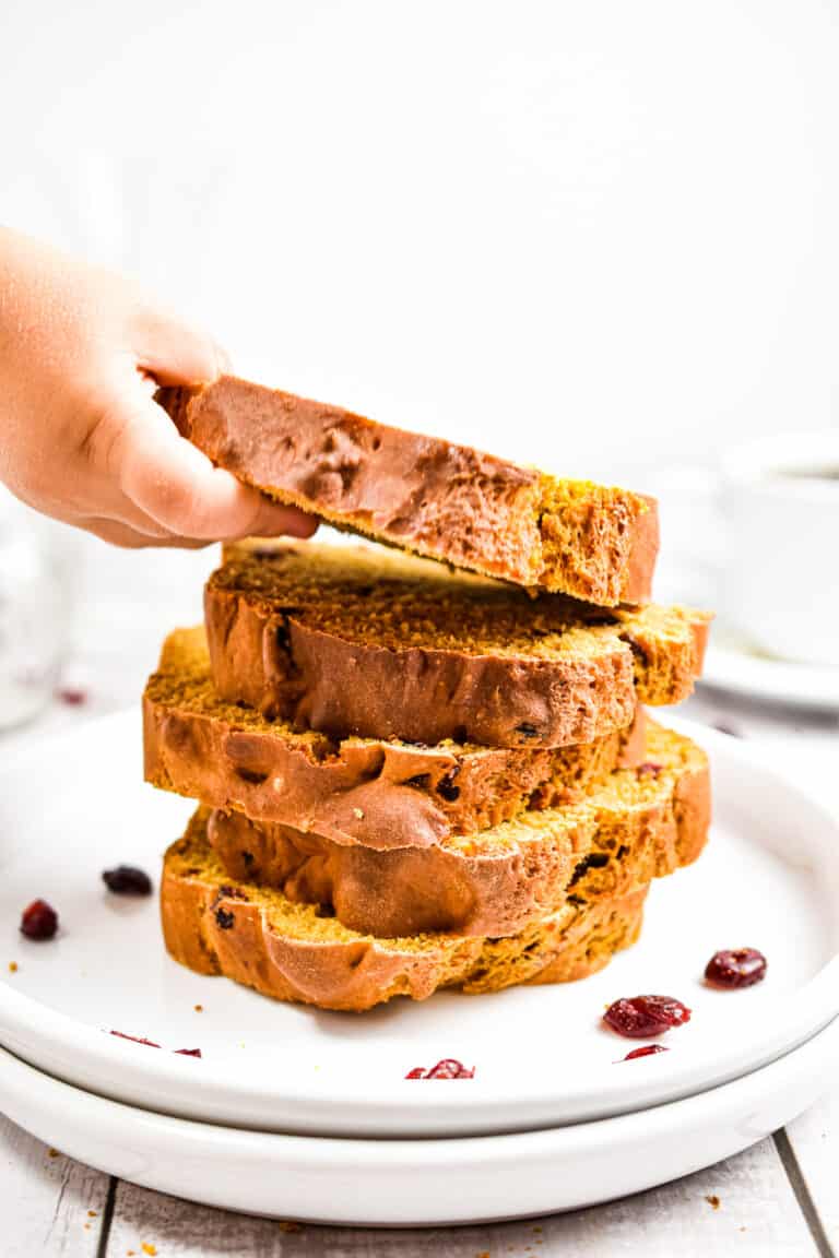 A child's hand is reaching for a stack of the pumpkin soda bread