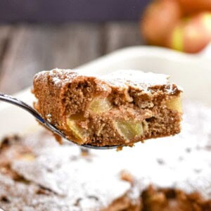 A slice of the all in one apple cake is lifted over the pan