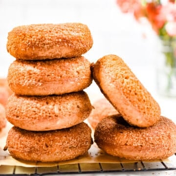 The sourdough apple cider donuts are stacked and one is leaning against the stack