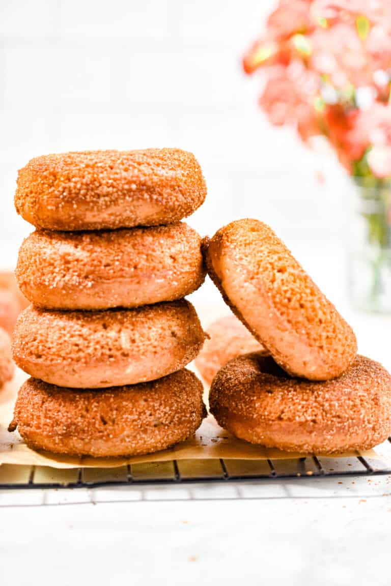 The sourdough apple cider donuts are stacked and one is leaning against the stack