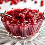 The cranberry sauce is in a glass bowl with oranges in the background