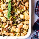 An overhead view of the stuffing in a baking dish with rosemary on it.