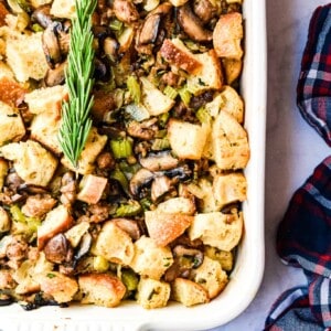 An overhead view of the stuffing in a baking dish with rosemary on it.