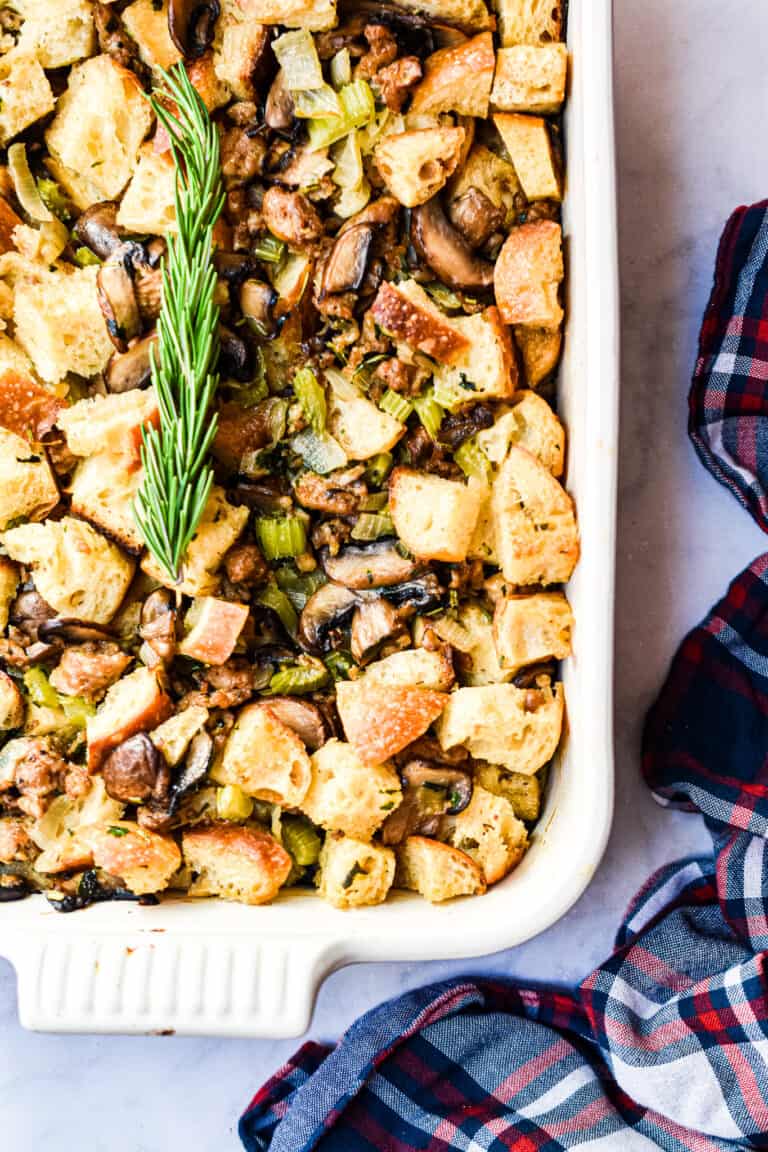 An overhead view of the stuffing in a baking dish with rosemary on it.