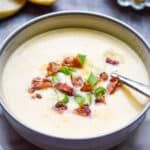A straight on view of the soup with bread and cheese in the background
