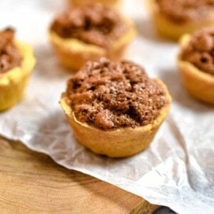 The mini walnut tarts are on a cutting board