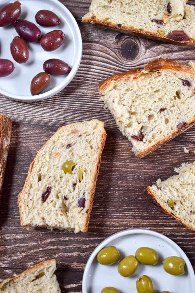 Slices of olive bread in instant pot are laid out with red and green olives