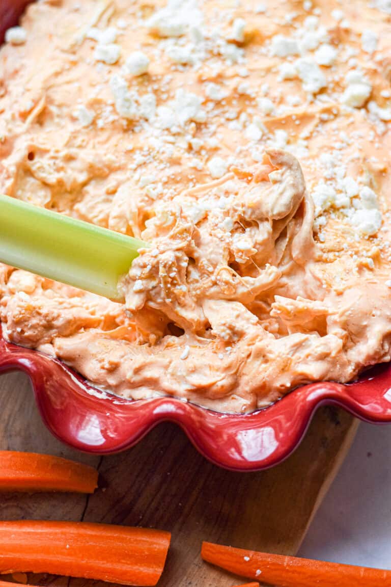 A celery stick is being dipped into the Instant Pot Buffalo Chicken Dip