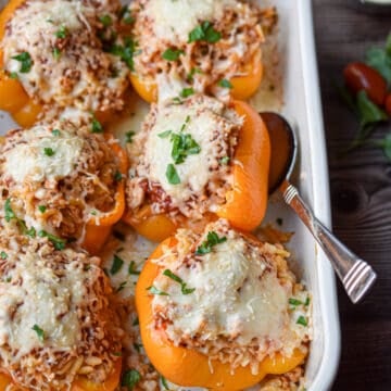 A spoon is underneath one of the chicken parmesan stuffed peppers.