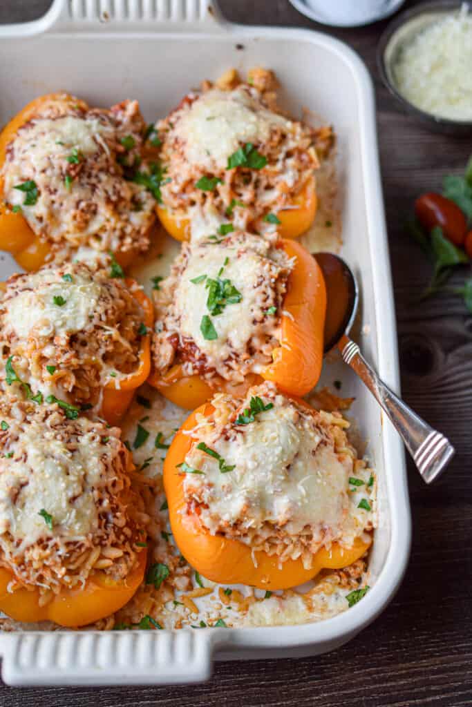 A spoon is underneath one of the chicken parmesan stuffed peppers.