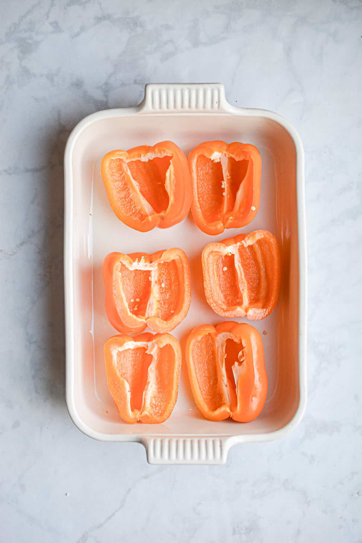 The raw peppers are in a baking dish.