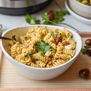A parsley leaf is on top of a bowl full of Instant Pot Feta Pasta.