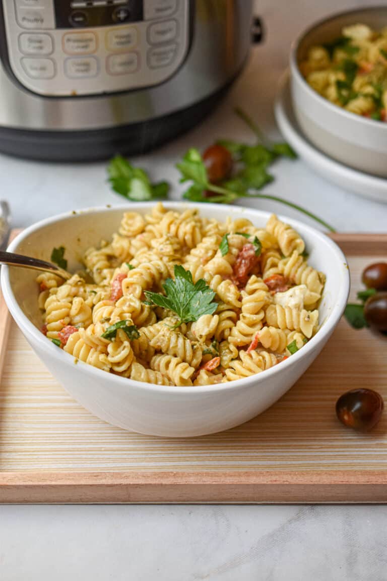 A parsley leaf is on top of a bowl full of Instant Pot Feta Pasta.