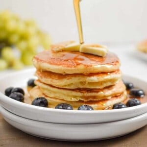 Maple Syrup is being poured over a stack of sourdough discard pancakes.