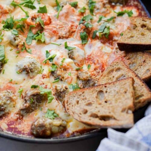 Crostini is in the skillet with the meatball sub dip.