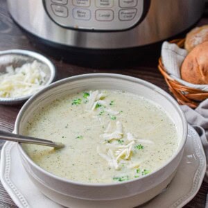 A bowl of Instant Pot broccoli cheddar soup is in front of an Instant Pot.