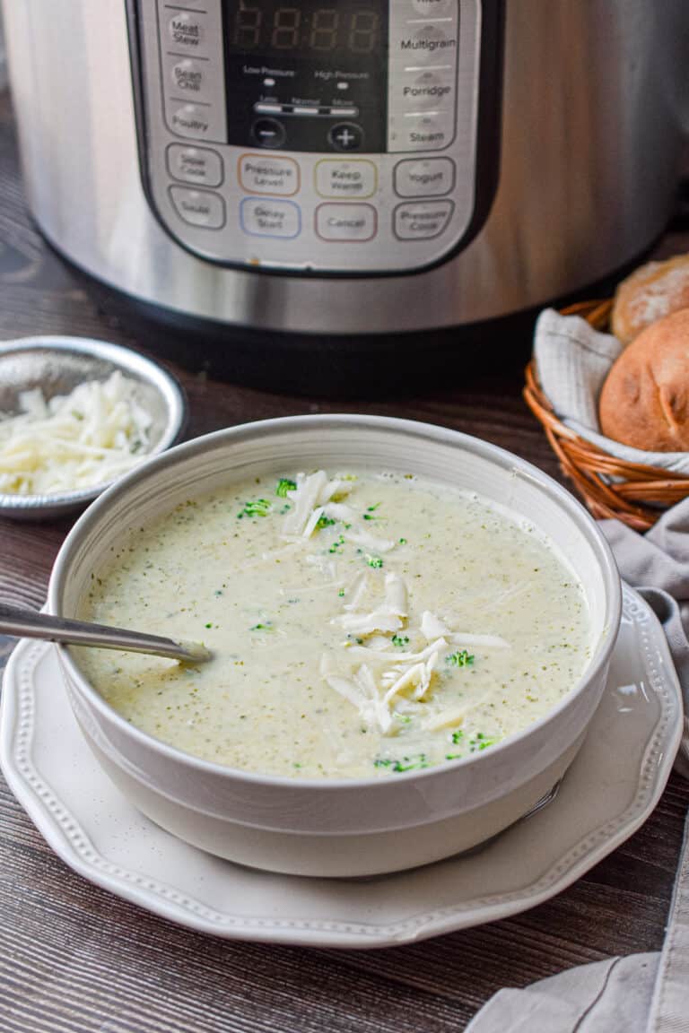 A bowl of Instant Pot broccoli cheddar soup is in front of an Instant Pot.