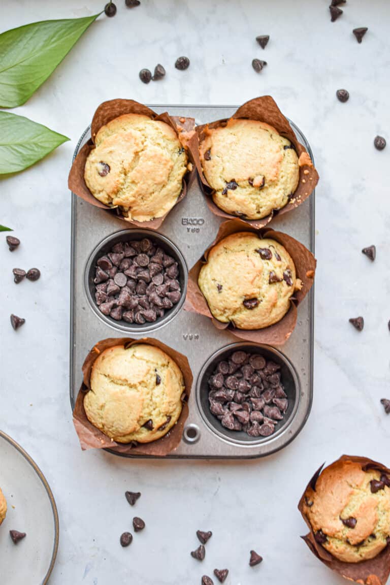 Two portions of the muffin tin are filled with chocolate chips and the other four sections are filled with thebaked muffins.