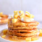Maple syrup is being poured onto the mango pancakes
