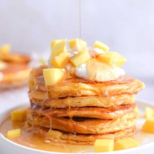 Maple syrup is being poured onto the mango pancakes