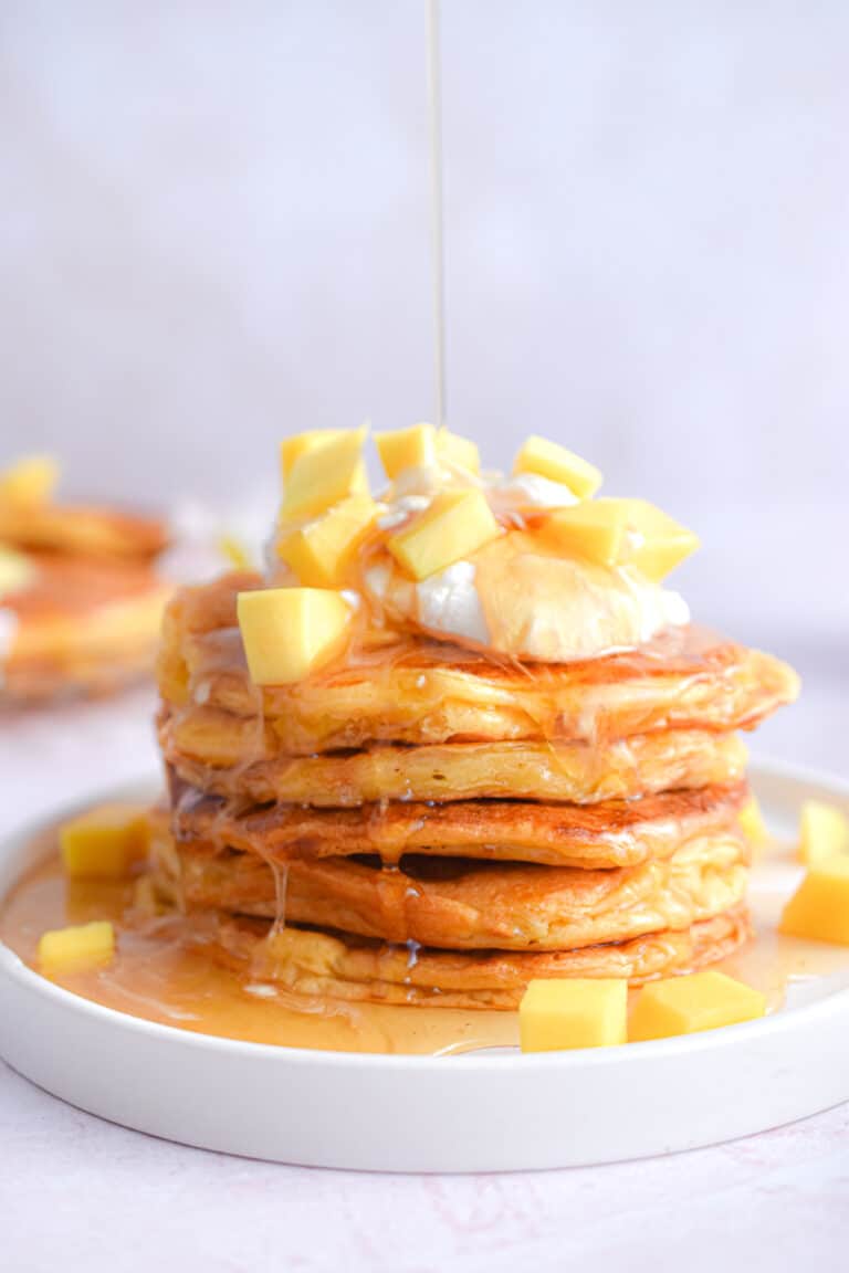 Maple syrup is being poured onto the mango pancakes