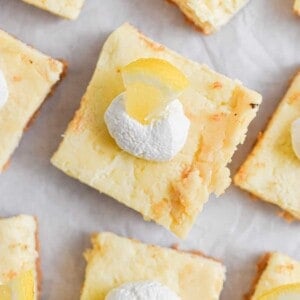 The lemon cheesecake bars are laid out on parchment paper.