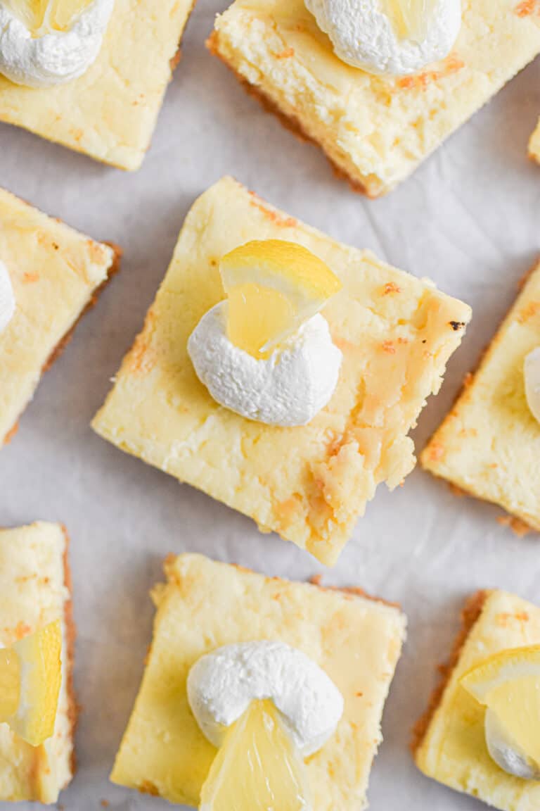 The lemon cheesecake bars are laid out on parchment paper.