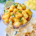 The mango habanero salsa is in a margarita cup surrounded by chips.