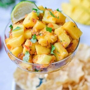 The mango habanero salsa is in a margarita cup surrounded by chips.