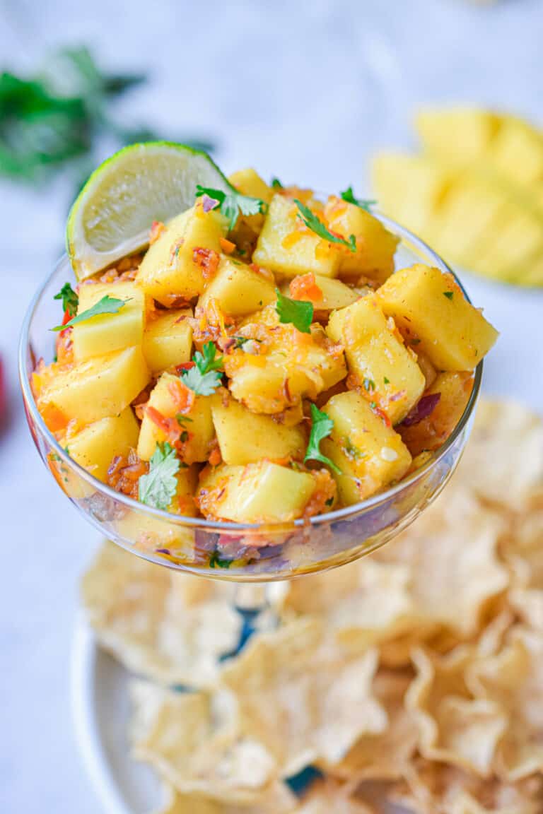 The mango habanero salsa is in a margarita cup surrounded by chips.