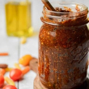 The pesto rosso is in a mason jar with a wooden spoon coming out of it.