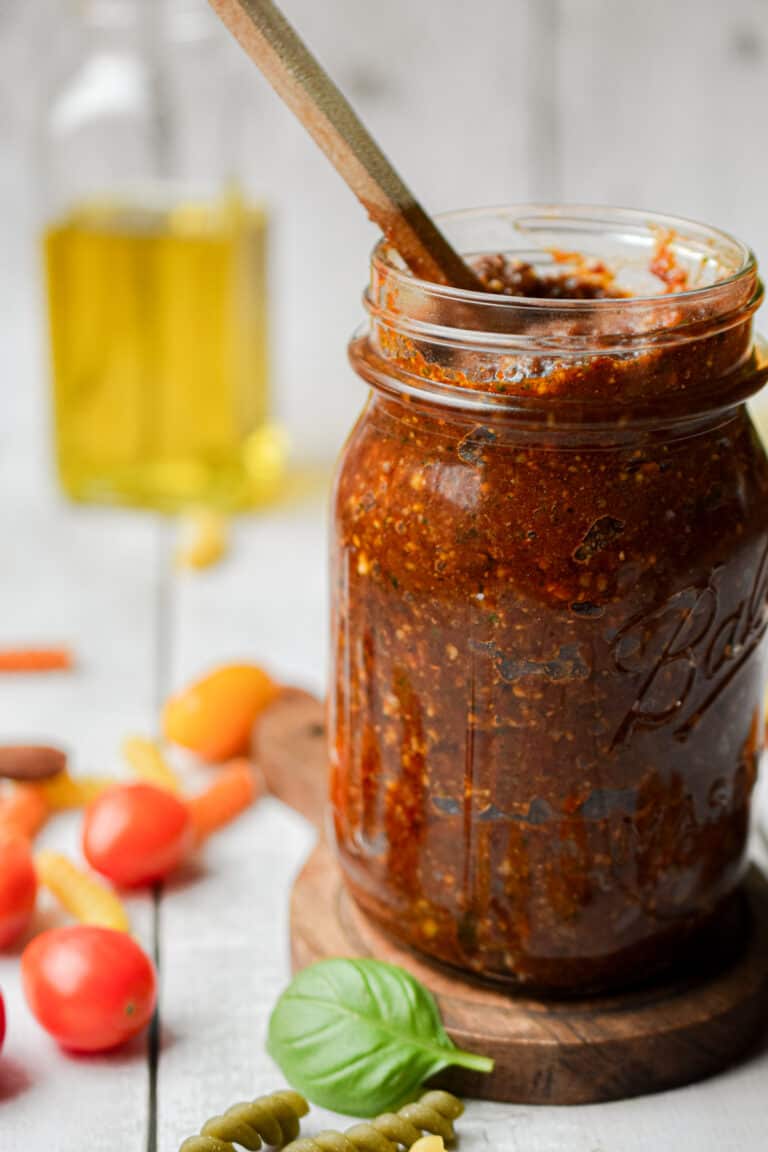The pesto rosso is in a mason jar with a wooden spoon coming out of it.