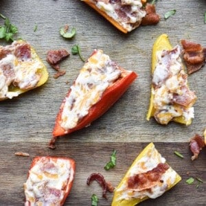 The bacon stuffed mini peppers are on a cutting board.